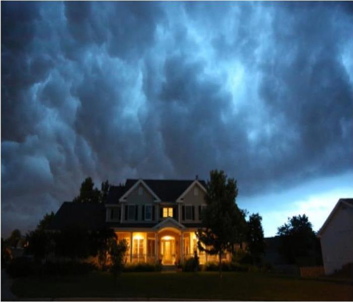 dark gray clouds above a house with evening lights on