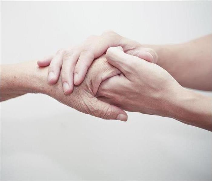 The hand of an elderly person holding hand of a younger person
