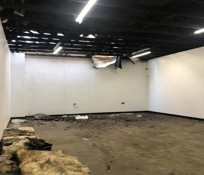 warehouse with concrete floor, white walls, dark soot and smoke stained walls